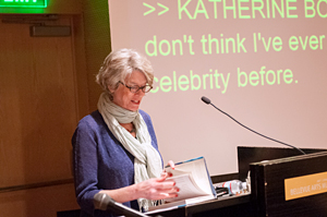 Katherine Bouton reads at the Bellevue Arts Museum with CART Captioning behind her. 